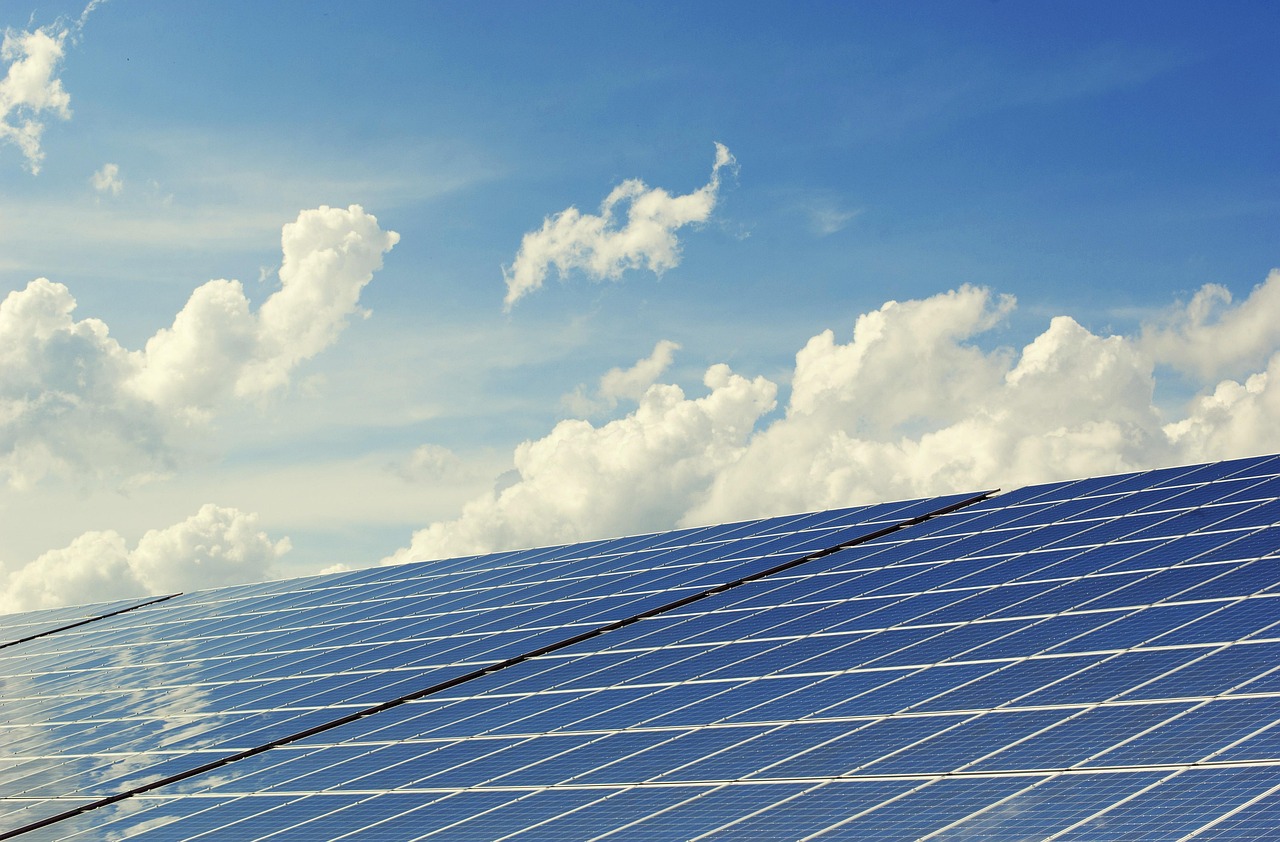 Rows of solar panels beneath a bright sky